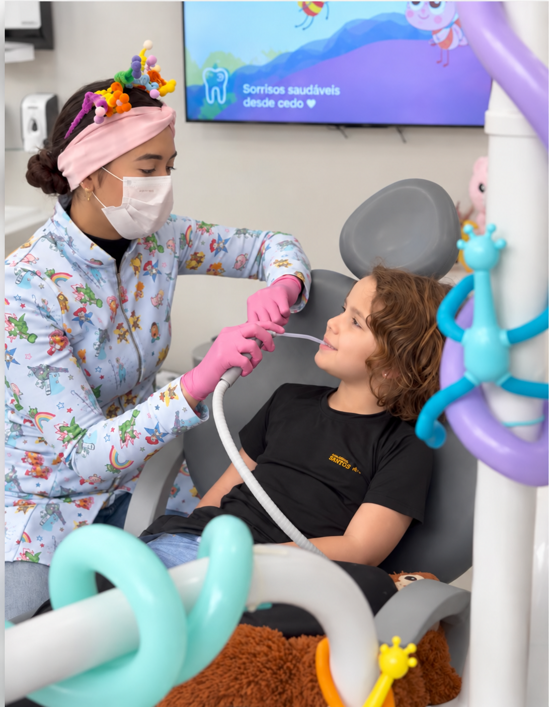 Dra. Giullia atendendo uma criança na cadeira odontológica do consultório.
